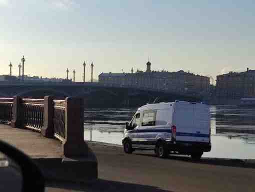 На Васильевском острове у спуска с Благовещенского моста стоит полицейский автомобиль . Рядом располагается…